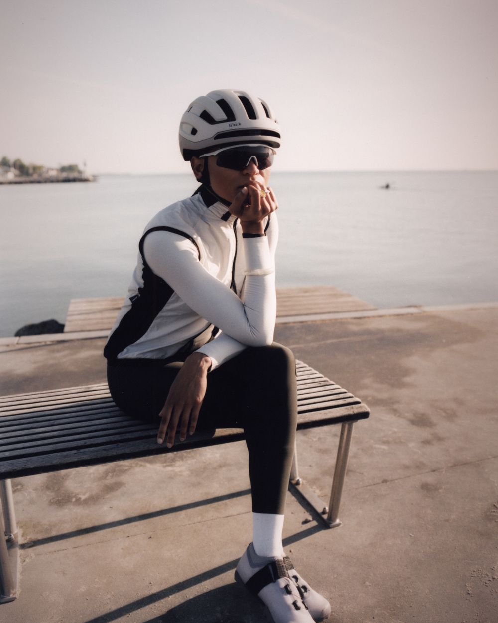 Rider in summer kit sitting on a bench by the water
