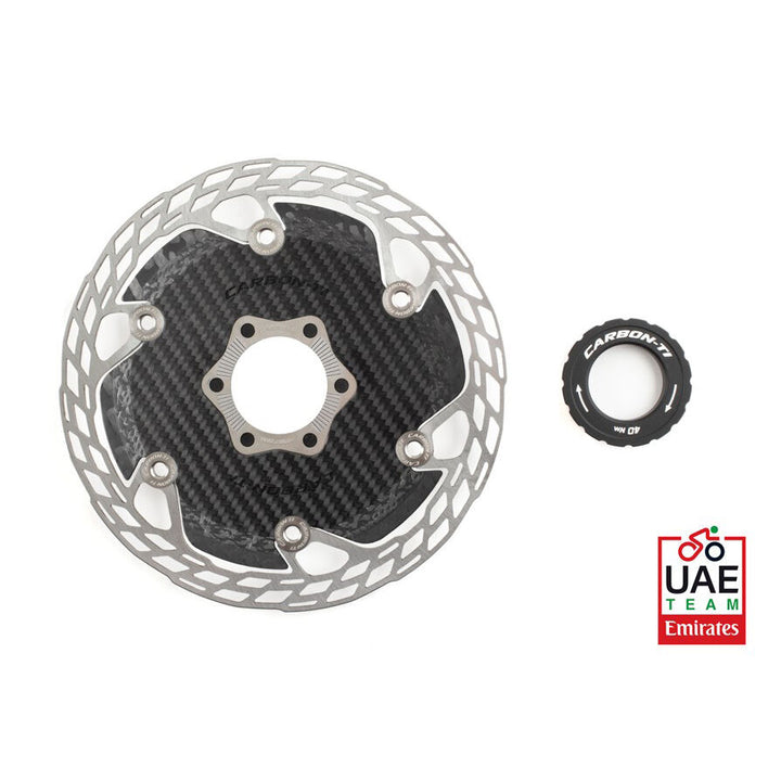 Disc brake rotor with carbon fiber insert and small black component on a white background, featuring UAE Team Emirates logo.