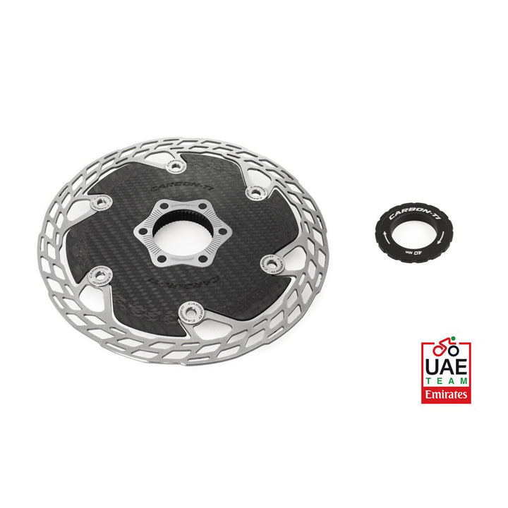 Carbon fiber disc brake rotor with a small washer on a white background, featuring the UAE Team Emirates logo.