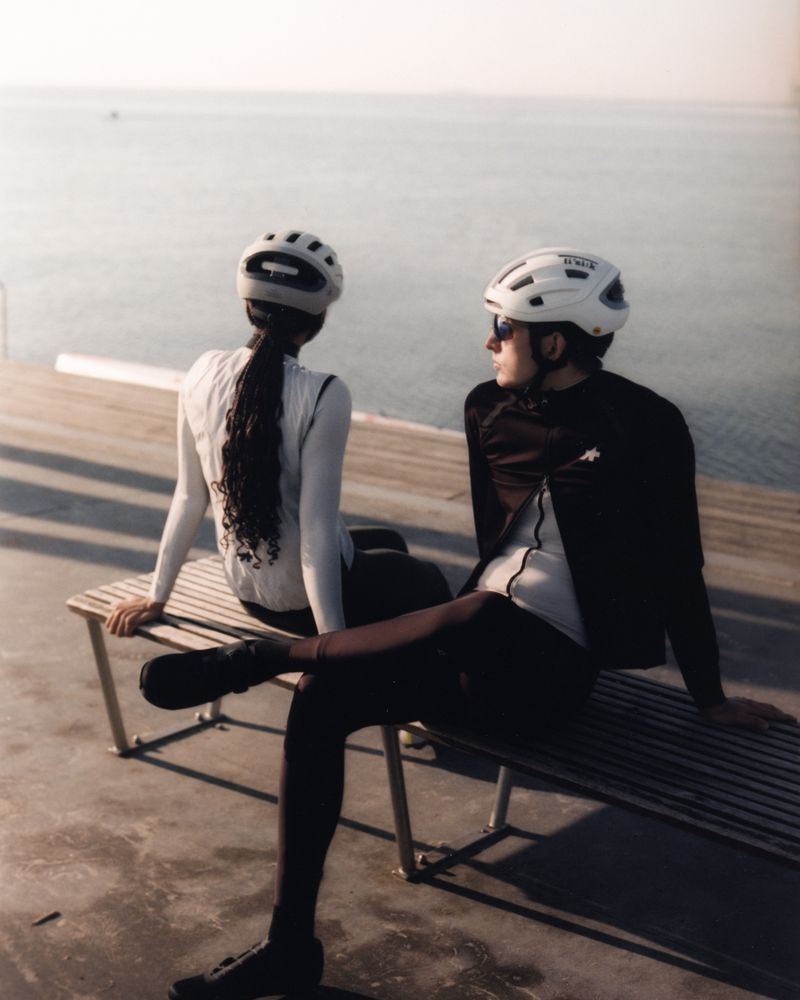 Two riders resting on a bench by the sea