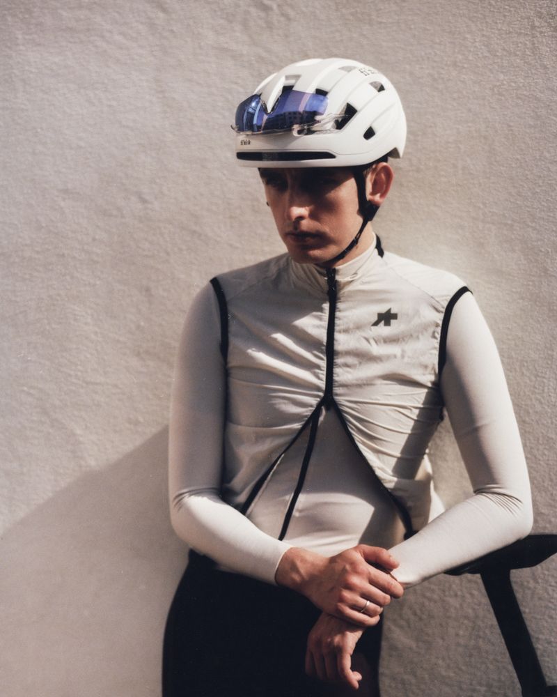 Rider in a light grey Assos layer against a wall
